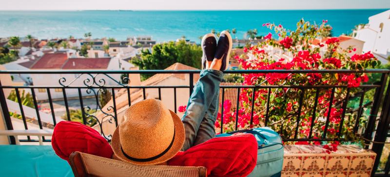 turismo y viviendas. Hombre descansando en la terraza de un piso con vistas al mar