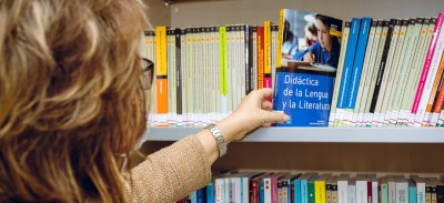 Mujer colocando un libro en la biblioteca de la Universidad Isabel I