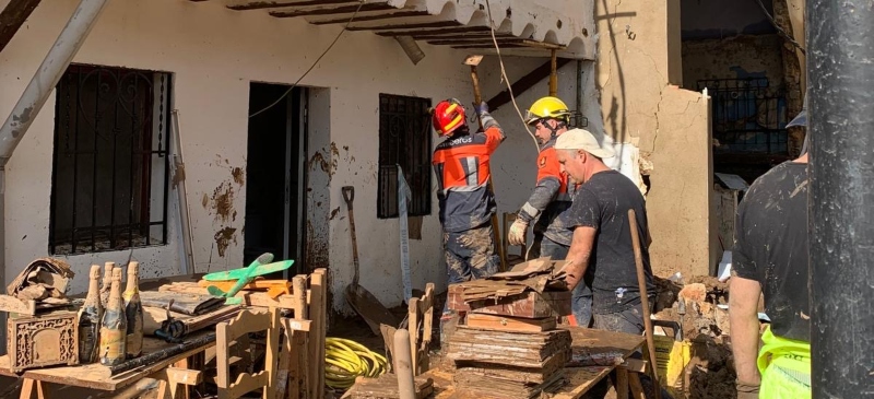 grupo de bomberos y voluntarios retirando enseres