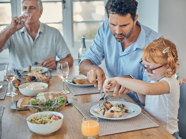 Padre que ayuda a su hija a cortar la carne en el plato