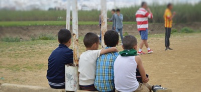 Niños migrantes viendo un partido de fútbol.