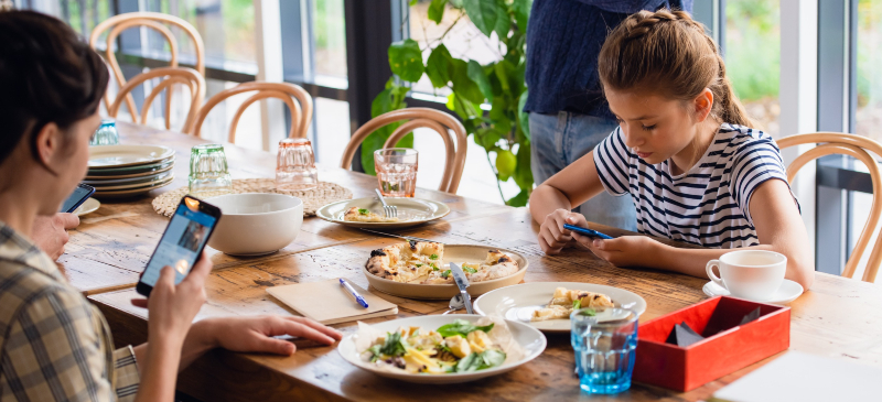 Niña con smartphone en un restaurante